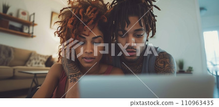 Multiracial young couple enjoying quality time together while watching laptop on sofa at home Multiracial young couple enjoying quality time together while watching laptop on sofa at home 110963435