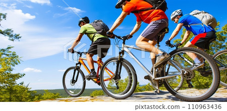 Exciting group of mountain bikers speeding downhill on a thrilling descent adventure Exciting group of mountain bikers speeding downhill on a thrilling descent adventure 110963436
