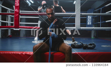 African American boxer sits near boxing ring and wraps hands 110964164