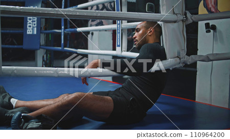 Tired and exhausted African American fighter sits in ring corner 110964200