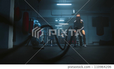 Female boxer does cardio or endurance workout with ropes in gym Female boxer does cardio or endurance workout with ropes in gym 110964206