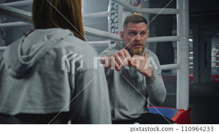 Female boxer sits on ring and talks with male trainer about fight 110964233