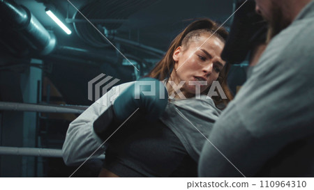 Female fighter in boxing gloves practicing fighting technique Female fighter in boxing gloves practicing fighting technique 110964310