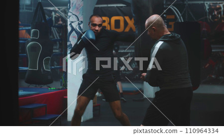 Confident African American fighter hits punching bag Confident African American fighter hits punching bag 110964334