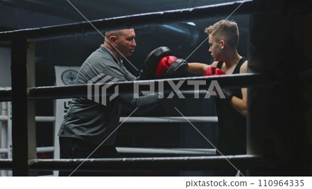 Professional coach teaches young boxer how to dodge punches Professional coach teaches young boxer how to dodge punches 110964335