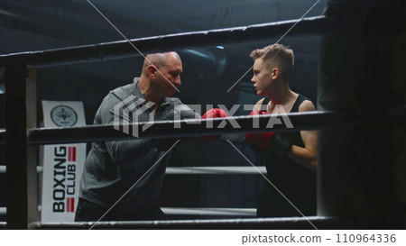 Professional coach teaches young boxer how to dodge punches Professional coach teaches young boxer how to dodge punches 110964336