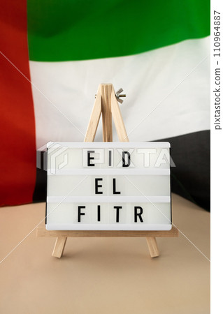 EID EL FITR - Eid Mubarak - Happy Holidays text frame on United Arab Emirates waving flag made from silk material. Public holiday celebration background. The National Flag of UAE. Commemoration Day 110964887