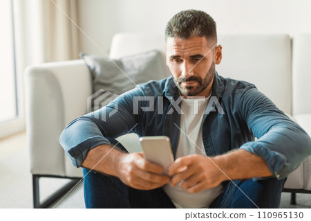Middle aged guy texting on smartphone while having issues indoor 110965130