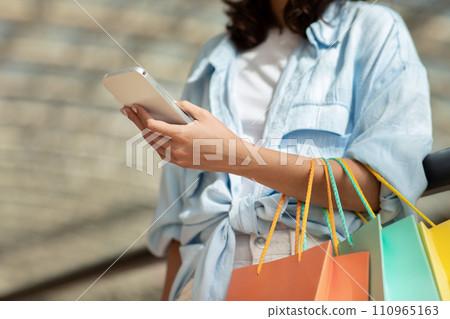 Young european lady with many shopping bags in hand, enjoy online shopping on mobile phone Young european lady with many shopping bags in hand, enjoy online shopping on mobile phone 110965163