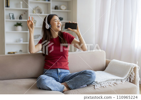 Favorite Leisure. Asian Woman Singing While Listening Music On Smartphone At Home Favorite Leisure. Asian Woman Singing While Listening Music On Smartphone At Home 110965224