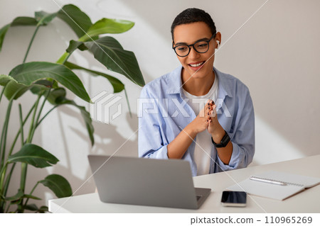 Positive young latin lady manager, freelance, teacher in wireless headphones, glasses has video call Positive young latin lady manager, freelance, teacher in wireless headphones, glasses has video call 110965269