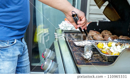 Unrecognized man is cooking grilled vegetables and meat sausages on stainless BBQ grill. Food and cuisine concept. 110965331