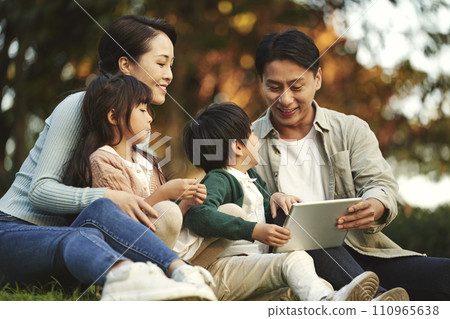 happy asian family with two children having a good time sitting on grass relaxing in city park 110965638