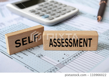 Self assessment text on wooden blocks with tax form and calculator background. Taxation concept. 110966022