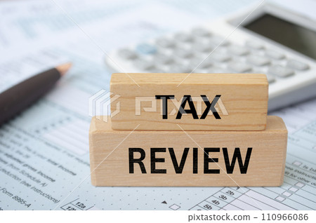 Tax review text on wooden blocks with tax form and calculator background. Taxation concept. 110966086