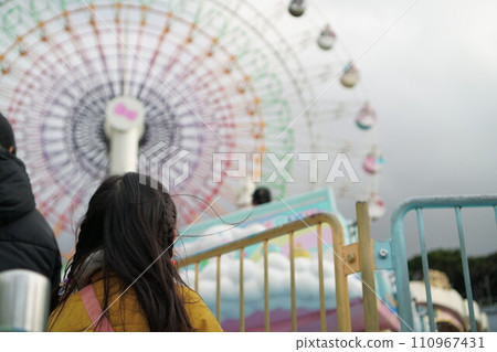 一個女孩在一個有大摩天輪的遊樂園排隊等待景點 110967431