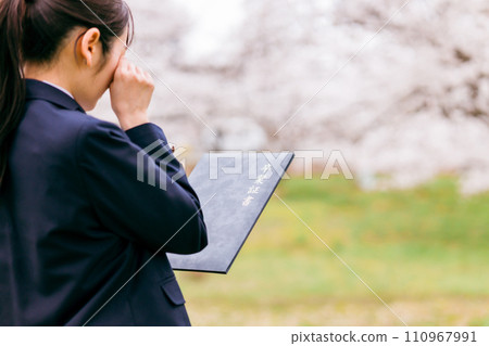 High school/high school girl wiping tears while holding a diploma (graduation, graduates, graduation ceremony, cherry blossoms, schoolyard) 110967991
