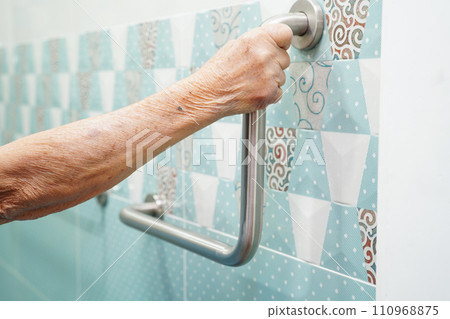 Asian elderly old woman patient use toilet support rail in bathroom, handrail safety grab bar, security in nursing hospital. 110968875