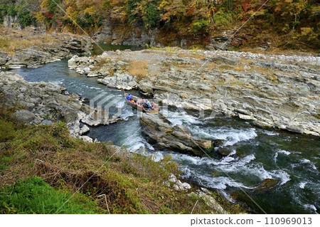A pleasure boat sailing down the Nagatoro Line on the Arakawa River, which flows near the southern end of the rocky pavement of the Nagatoro Valley with its autumn leaves. 110969013
