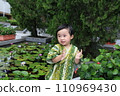 a child clapping hands at a water lily garden, dressed up in Japanese costume  110969430