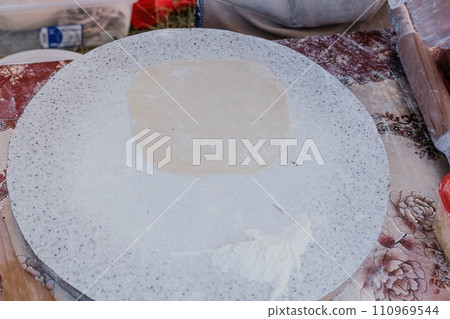 woman's hands making qutab or chebureki with a rolling pin and minced meat onion in dough for culinary concepts related to Azerbaijani, Tatar and Greek cuisine, as well as empanadas in Latin America. woman's hands making qutab or chebureki with a rolling pin and minced meat onion in dough for culinary concepts related to Azerbaijani, Tatar and Greek cuisine, as well as empanadas in Latin America. 110969544