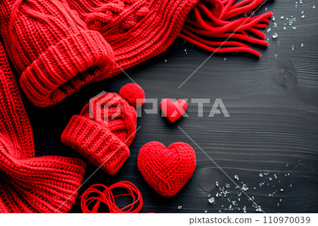 Red knitted scarf, hearts and snowflakes on black wooden background Red knitted scarf, hearts and snowflakes on black wooden background 110970039