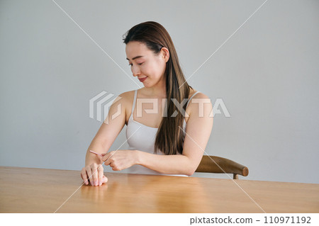 A woman in her 30s shaving her arm hair with a ladies razor 110971192