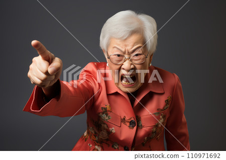 An elderly woman in floral red jacket points assertively, her facial expression conveying a strong message or demand. 110971692