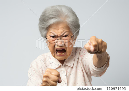Elderly angry Asian woman frowning and waving her fists indignantly Elderly angry Asian woman frowning and waving her fists indignantly 110971693