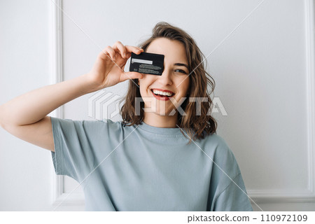 Joyful Woman Holding Credit Card, Shopping Online Happily. Happy Woman Playfully Peeking through Joyful Woman Holding Credit Card, Shopping Online Happily. Happy Woman Playfully Peeking through 110972109