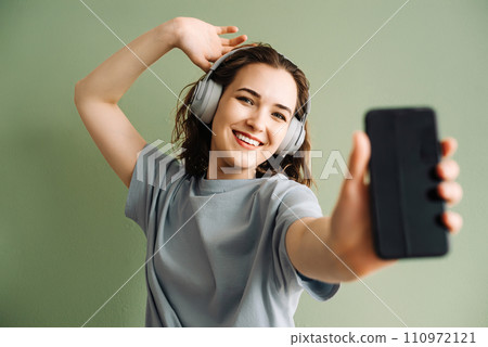 A young woman wearing wireless headphones listening to music, dancing. Energetic Beats. Young Lady A young woman wearing wireless headphones listening to music, dancing. Energetic Beats. Young Lady 110972121