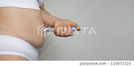 Female model patient making Semaglutide Injection Pen in her Stomach.  110972328