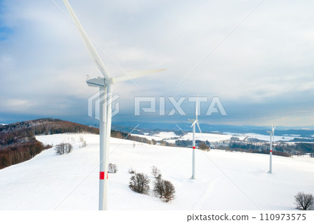 Aerial view of wind turbines or windmills for electricity production in the field in winter. Renewable and green energy concept 110973575