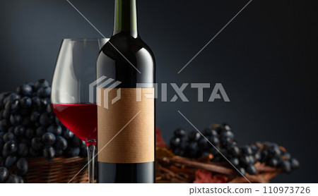 Bottle and glass of red wine with blue grapes. Bottle and glass of red wine with blue grapes. 110973726