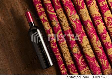 Bottle of red wine and retro tapestry with floral ornament. Bottle of red wine and retro tapestry with floral ornament. 110973765