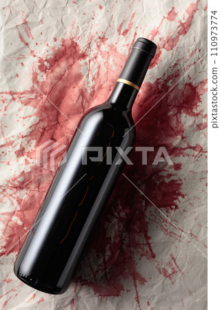 Bottle of red wine on a background with stains of wine. 110973774