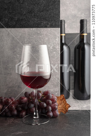 Red wine with grapes and dried vine leaves. 110973775
