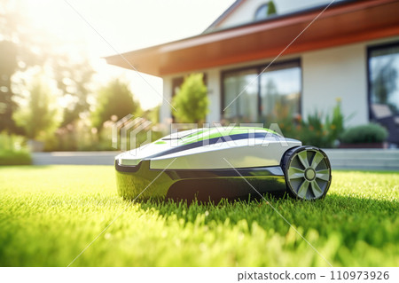 Automatic robotic lawn mower on a green lawn with modern house in background. AI content Automatic robotic lawn mower on a green lawn with modern house in background. AI content 110973926
