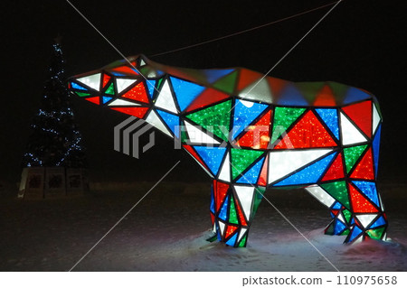 Bear garland. Multi-colored sparkling electric New Year Christmas bear on snow at night. Installation figure, architectural form for decorating streets on holiday. Red, blue, green, white triangle Bear garland. Multi-colored sparkling electric New Year Christmas bear on snow at night. Installation figure, architectural form for decorating streets on holiday. Red, blue, green, white triangle 110975658
