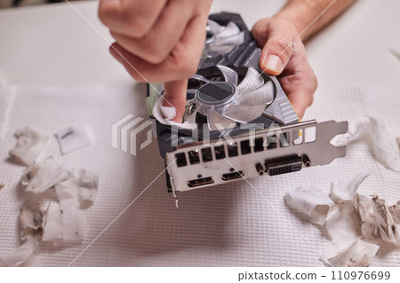 Changing the thermal paste on the graphics processor. Disassembled graphics card on the table. Old graphics card service. Changing the thermal paste on the graphics processor. Disassembled graphics card on the table. Old graphics card service. 110976699