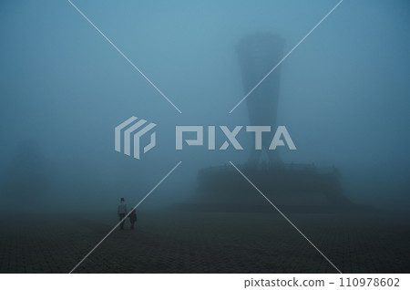 backs of mother woman with child son walking in a misty foggy mystical park in evening. A misty landscape with people in autumn in a misty fog mist haze backs of mother woman with child son walking in a misty foggy mystical park in evening. A misty landscape with people in autumn in a misty fog mist haze 110978602