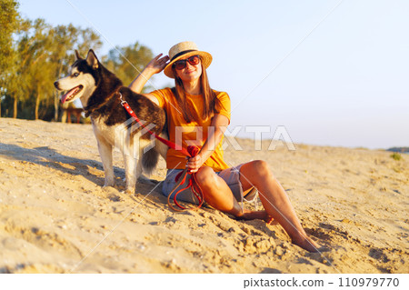 Woman with Husky Dog Enjoying Beach Sunset Woman with Husky Dog Enjoying Beach Sunset 110979770