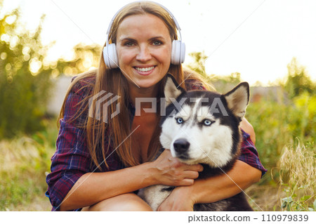 Smiling Woman Hugging Her Husky Dog Outdoors 110979839