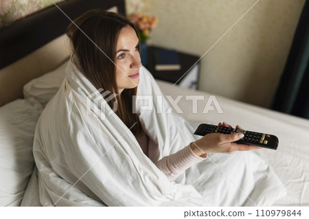 Woman Wrapped in Blanket Watching Television in Bed 110979844