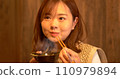 Young woman eating dinner 110979894