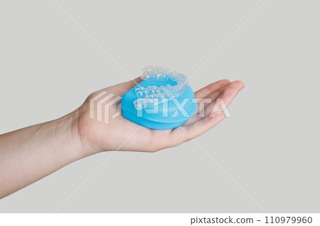 Human hand holds invisible aligners plastic braces dentistry retainers 110979960