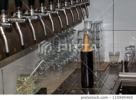 Behind the counter. Women's hands beautifully and easily pour beer into a bottle. Behind the counter. Women's hands beautifully and easily pour beer into a bottle. 110980460