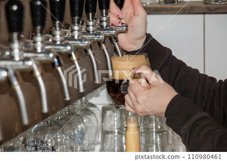 Behind the counter. Women's hands beautifully and easily pour beer into a bottle. Behind the counter. Women's hands beautifully and easily pour beer into a bottle. 110980461