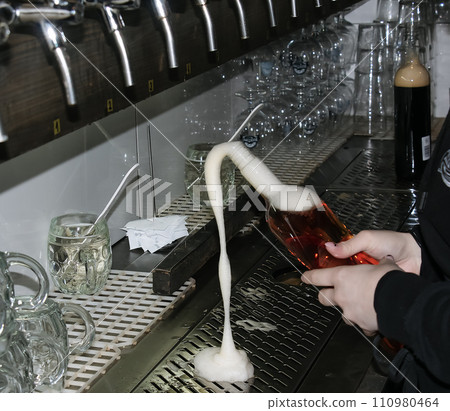Behind the counter. Women's hands beautifully and easily pour beer into a bottle. Behind the counter. Women's hands beautifully and easily pour beer into a bottle. 110980464