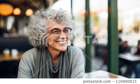 Generative AI The image shows an elderly woman with curly gray hair, wearing glasses and smiling in a cafe setting. Generative AI The image shows an elderly woman with curly gray hair, wearing glasses and smiling in a cafe setting. 110980815